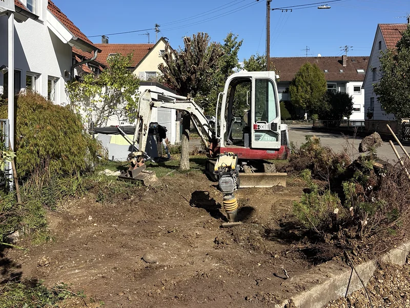 Minibagger und Stampfer bei Erdarbeiten in einem Vorgarten