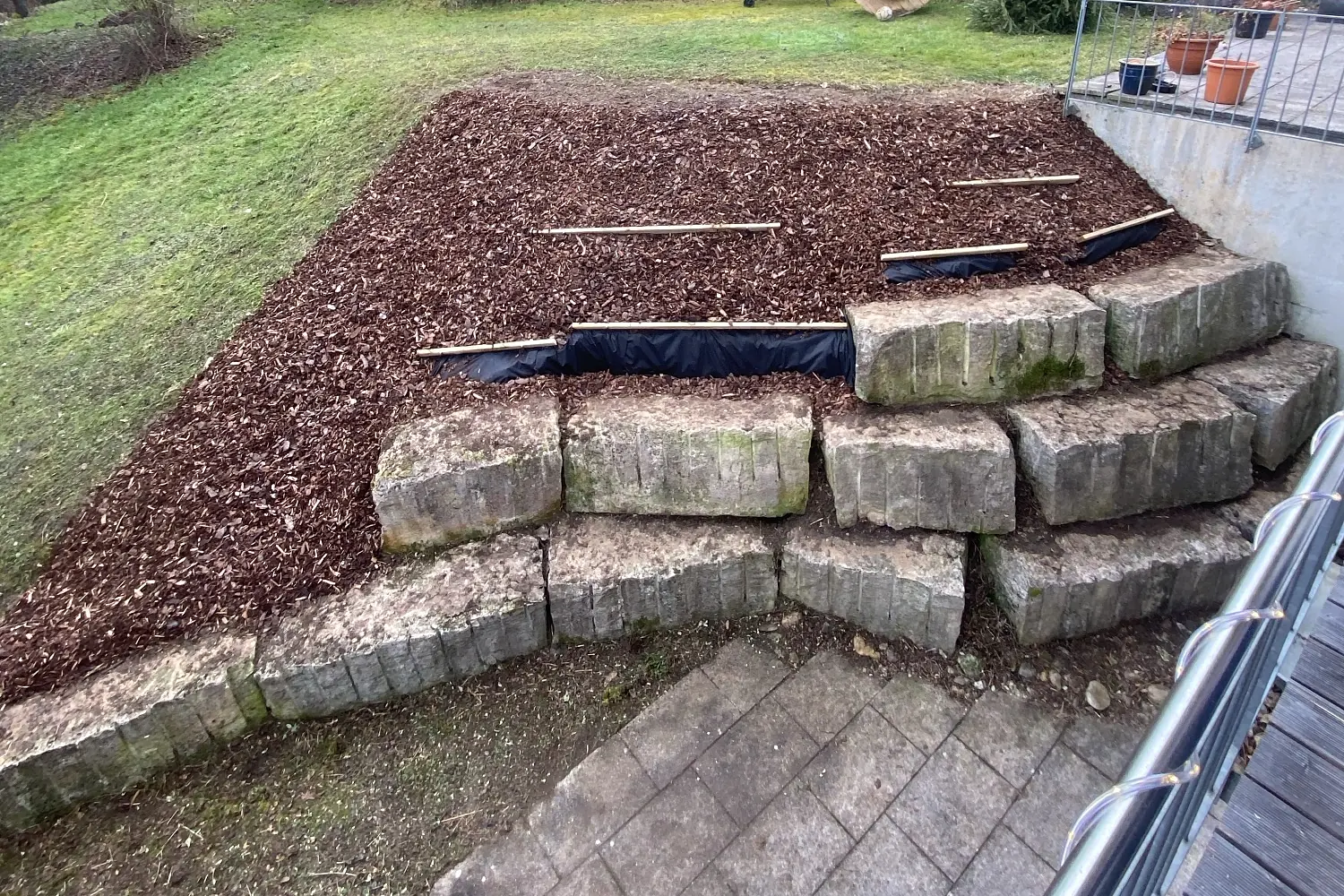 Nachher: Hang mit Natursteinblöcken, Unkrautvlies und Rindenmulch