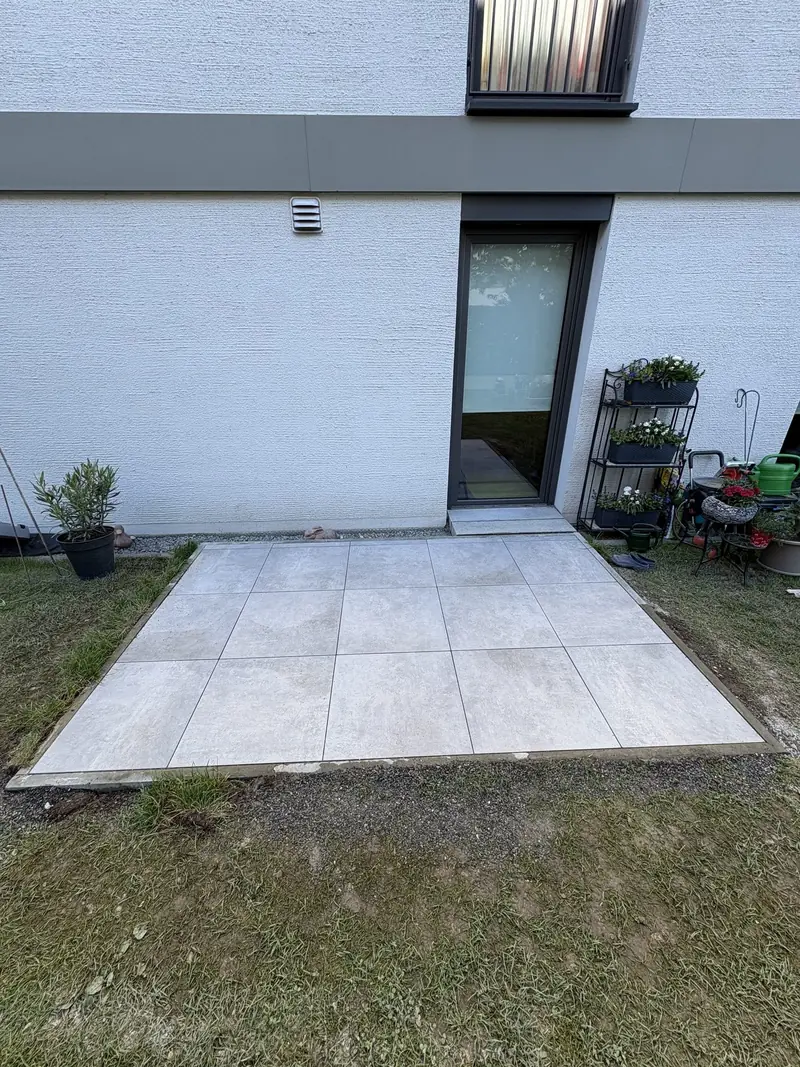 Neue Terrasse aus hellen Keramikplatten vor einer Terrassentür